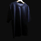 Navy blue t-shirt on a hanger against a plain wall.