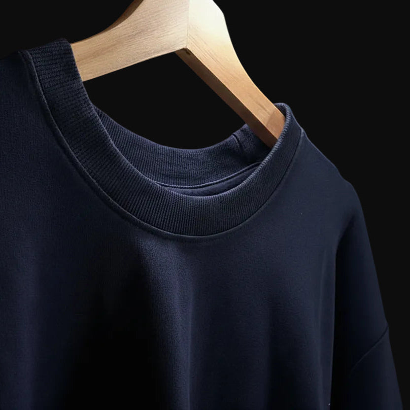 Navy blue sweater on a wooden hanger against a neutral background