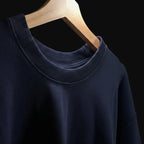 Navy blue sweater on a wooden hanger against a neutral background