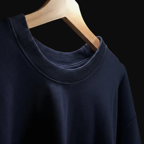 Navy blue sweater on a wooden hanger against a neutral background
