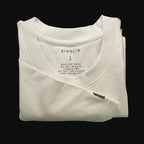 Folded white oversized tee with label on a black background