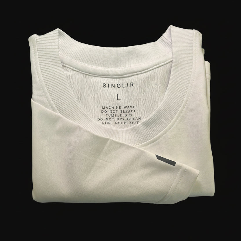 Folded white oversized tee with label on a black background